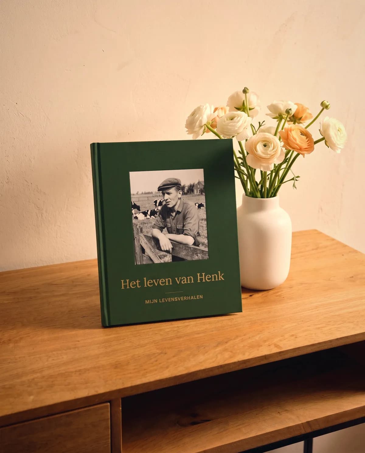 Un livre Nos Histoires avec des fleurs sur la table, prêt à être offert à papi et mamie.